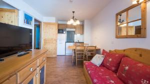 ein Wohnzimmer mit einem roten Sofa und einer Küche in der Unterkunft T Bergerie A N104 2P4 in Forest des Baniols