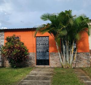 an orange building with an orange door and a palm tree at Las Palmeritas in Ahuachapán