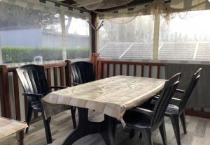 a table and chairs sitting on a porch with a table and a table and chairs at L'Aurore - Mobil-home climatisé - Piscine in La Bernerie-en-Retz