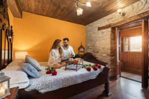 Un hombre y una mujer sentados en una cama en La Congosta, mágica aldea rodeada de montañas, en La Plaza