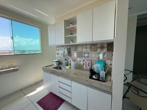 una cucina con mobili bianchi, un lavandino e una finestra di Apartamento com duas suítes! a Macapá