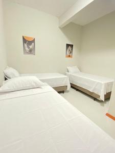 a white room with two beds in it at Pousada Âncora in Gravataí
