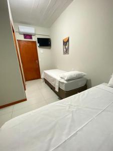 a hotel room with two beds and a window at Pousada Âncora in Gravataí