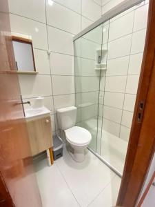 a bathroom with a toilet and a glass shower at Pousada Âncora in Gravataí