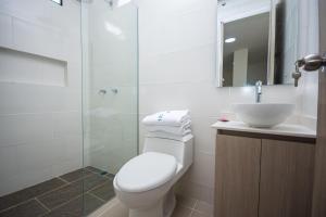 um banheiro com vaso sanitário, pia e chuveiro em Apartahotel Ces em Medellín