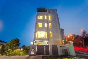 ein hohes weißes Gebäude mit eingeschalteten Lichtern in der Unterkunft Tripli The Pinakin Stays in Varanasi