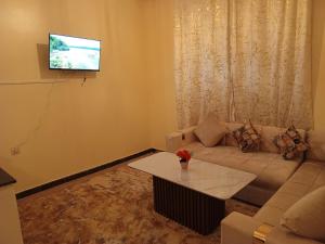 a living room with a couch and a tv on a wall at Royal Stay Apartment in Benguerir