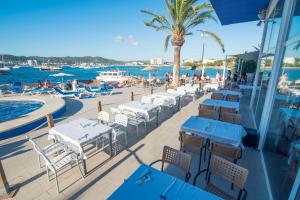 a restaurant with tables and chairs next to the water at azuLine Hoteles Mar Amantis & II in San Antonio Bay