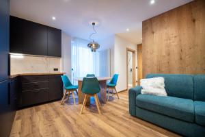 a living room with a blue couch and a table and chairs at Tito Apartments in Ortisei