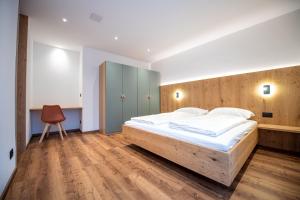 a bedroom with a large bed and a chair at Tito Apartments in Ortisei