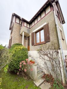 ein Haus mit einem Fenster und einigen Büschen in der Unterkunft Maison avec jardin dans le centre de Cabourg in Cabourg