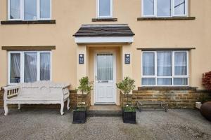 a white bench sitting in front of a house at Host and Stay - 36 Hardy Meadows in Grassington
