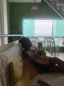 a woman laying on a couch playing a guitar at Hostel Feminino Sol de Maria in Salvador