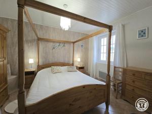 une chambre avec un lit à baldaquin en bois et une fenêtre dans l'établissement Gite du soleil levant, à Lacropte