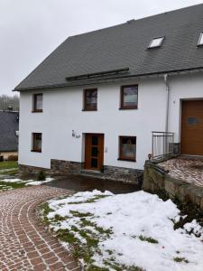 een wit huis met sneeuw ervoor bij Ferienwohnungen Friedrich - im Herzen des Erzgebirges in Mildenau