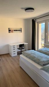 een slaapkamer met een bed, een bureau en een raam bij Ferienwohnung Amseltraum in Seeboden