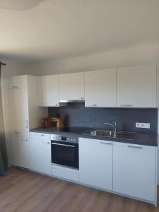 een keuken met witte kasten en een spoelbak bij Ferienwohnung Amseltraum in Seeboden