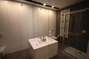 biała łazienka z umywalką i prysznicem w obiekcie Apartament na Złotej w Kielcach