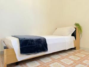 a white bed with a blue blanket on it at Casa Tonia - Baia Verde in Baia Verde