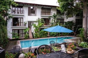 a hotel with a swimming pool and a blue umbrella at Ceiba Studios in Zihuatanejo