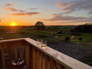 Dos vasos de cerveza en una barandilla de madera con vacas. en West Coast Whistlestop, en Ochiltree