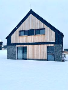 a large wooden building with snow in front of it at Nad Soutokem in Volary