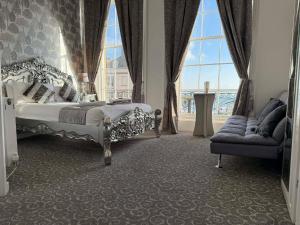 a bedroom with a bed and a couch and a window at The Jubilee Hotel West- with NEWLY REFURBISHED SPA FACILITIES - GAMESPIT - AND SMOKEHOUSE in Weymouth