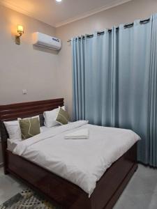 een slaapkamer met een groot bed met blauwe gordijnen bij Kibs apartments in Dodoma