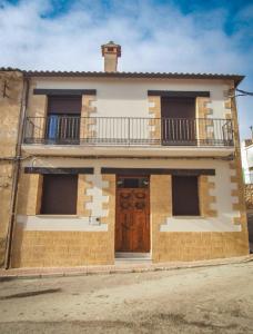 a house with a balcony and a wooden door at El Origen in Carboneras de Guadazaón