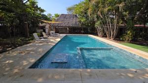 a swimming pool with chairs and a house at Hotel Zelen in Tamanique
