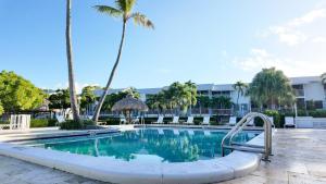 a swimming pool with palm trees in a resort at New Lagoon-front townhouse with Marina Day Dreams Key Largo in Key Largo