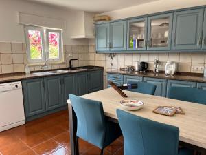 een keuken met blauwe kasten en een houten tafel met stoelen bij Quinta Samor in Aljezur