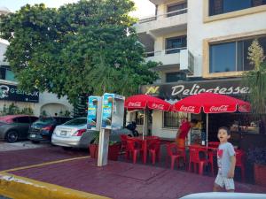un joven parado junto a un restaurante con sombrillas de cocacola en Casa Pok Tapok, en Cancún