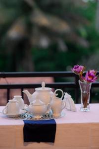 een theeservies op een tafel met een vaas bloemen bij Seaside Serenity Resort in Hiriketiya