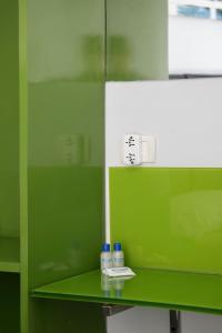 a green bathroom with a mirror and two bottles on a shelf at America Del Sur Hostel Buenos Aires in Buenos Aires