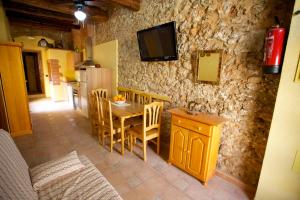 cocina con mesa y sillas y TV en una pared de piedra en Casa Llebra I, en Tortosa