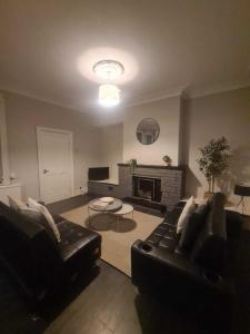 a living room with a black leather couch and a fireplace at Town Centre Apartments in Westoe