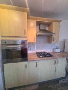 eine Küche mit weißen Schränken und einem Herd mit Backofen in der Unterkunft Cosy 3 bed House South Shields in Jarrow