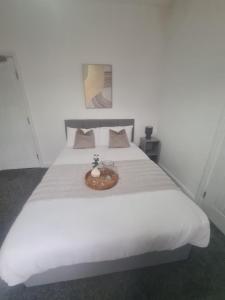 ein weißes Bett mit einer Holzschale darauf in der Unterkunft Cosy 3 bed House South Shields in Jarrow + 2 Fotos