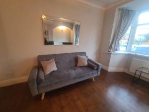 ein Sofa im Wohnzimmer mit Spiegel in der Unterkunft City North Apartment in Longbenton