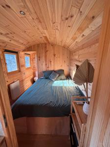 una camera da letto in una cabina di legno con un letto in esso di La Roulotte Saintaise a Saintes