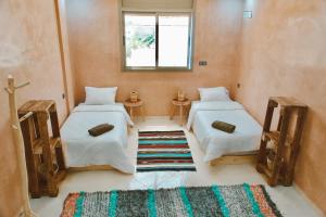 a room with two beds and a rug at Cool Surfers in Tamraght Ouzdar