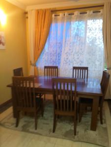 mesa de comedor con 4 sillas y ventana en Royal D8, en Mombasa