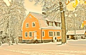 an orange house in the snow with trees at Ekebo Guesthouse in Svalöv +11 photos