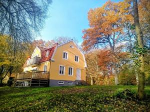 a large yellow house on a hill with trees at Ekebo Guesthouse in Svalöv
