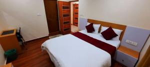 a bedroom with a large white bed with red pillows at RI Krishna Residency in Visakhapatnam