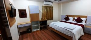 a bedroom with a bed and a desk and a television at RI Krishna Residency in Visakhapatnam