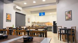a restaurant with tables and chairs and a kitchen at Limeira Plaza Hotel in Limeira