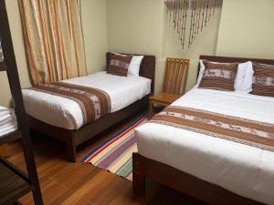 a bedroom with two beds and a chair at Huilka Mayu in Urubamba