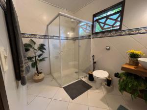 een badkamer met douche, toilet en raam bij Pousada Nalu - Camburi in São Sebastião +50 foto's